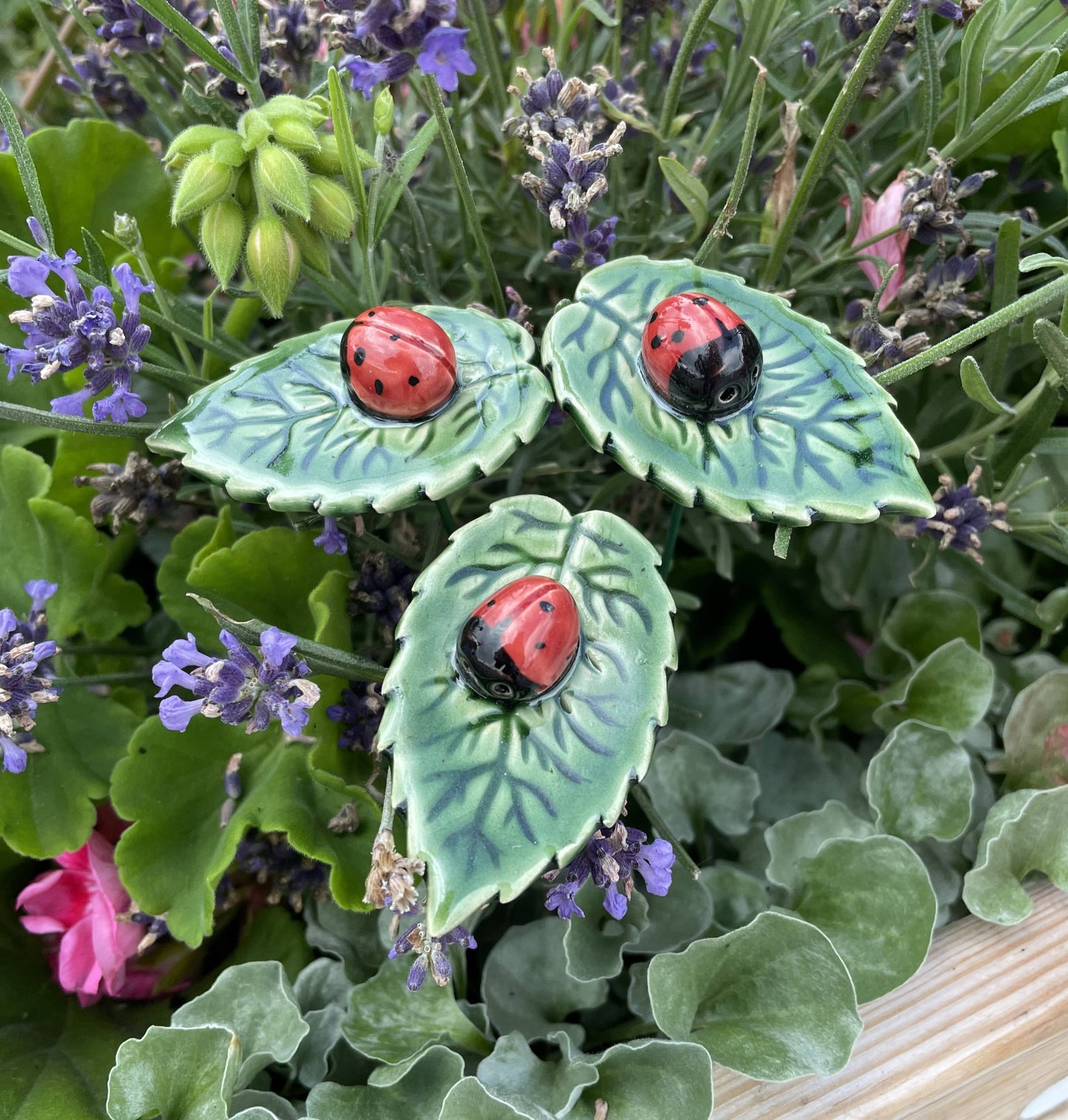 Mariquita de cerámica sobre hoja, flor de cerámica en tallo
